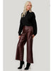 Woman wearing a black sweater and brown leather pants on a white background with 'Plus Size' branding.