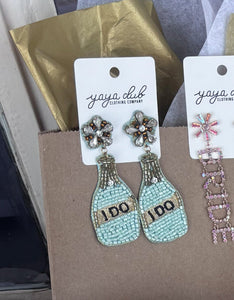 Earring set with 'BRIDE' pouch and flowers on a table