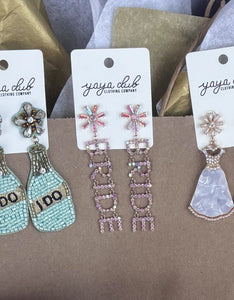 Earring set with 'BRIDE' pouch and flowers on a table