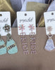 Earring set with 'BRIDE' pouch and flowers on a table